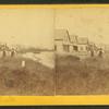 Two men by a fence in front of houses on the beach at Brant Rock.