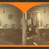 Interior of a residence showing chairs, table, pictures, and overhead light.