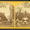 Civil war mounument in Clinton, decorated with garlands, 2 girls sitting on fence in foreground.