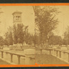 View of Clinton showing fence, trees, the steeple of a church and a bell tower.