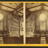 Interior of a church showing the altar, a large organ, and painted ceiling.