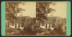 Three boys sitting on rocks in fron of a home.