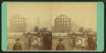 View of a fire in large industrial building with men spraying water.