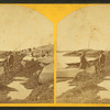 View of people with fishing poles standing by a boat on the shore.