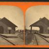 View of railroad depot with shed roof over tracks.