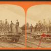 [Men in uniform on railroad flat car with fire engine(?).]