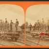Men in uniform on railroad flat car with fire engine(?).