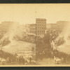 Crowd gathered watching small building on fire.