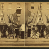 View of a store front decorated with flags with goods displayed.