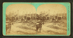 Buggies and wagons gathered around building under construction.