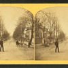 Residential street with people standing in and on the side of it.