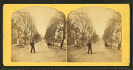 Residential street with people standing in and on the side of it.