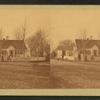 Unidentified home at a cross roads surrounded by a picket fence.