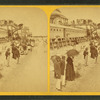 People on the beach in front of the Plank Walk, some with umbrellas.