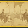 View of a man with a beard and top hat on a porch.