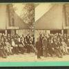 Group of men formally posed in front of large tent with sign that reads "Warren".