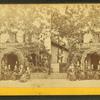 People posed in front and on the balcony of a cottage.