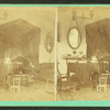 Interior view of a cottage showing chairs, table, mirror, lamps ,etc.