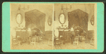 Interior view of a cottage showing chairs, table, mirror, lamps ,etc.