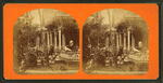 People sitting on the porch and in the yard of a cottage.