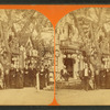 Group posing in front of cottages decorated with bunting and chinese lanters.