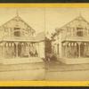 People on the porch of a decorated cottage.