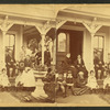 Group posing on the porch of a cottage.
