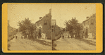 View of a street with a few people standing in it.