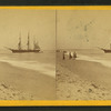 People on the shore looking at a ship.