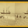 People on the shore looking at a ship.