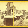 View of a commercial street lined with awmings, large horse team and wagon.