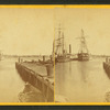 View of pier and ships docked in the harbor.