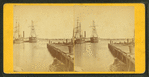 View of pier and ships docked in the harbor.