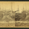 Men working on wharf in front of moored sailing vessels.