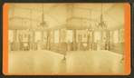 Interior of large room with piano, statues, benches and chairs lining it.