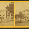 People in front of a large house with fence.