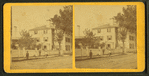 People in front of a large house with fence.