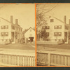 People in front of a large house with fence.