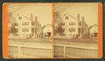 People in front of a large house with fence.