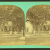 Group of people on the porch of a large house.