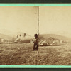 Man with a book on hill overlooking farms at Greylock Hall.