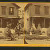 Miss Olive Jones sitting sidesaddle on her horse as others look on from the porch of a home.