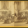 Interior view of a fair or church bazaar showing tables draped with flowers and arranged with items.