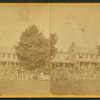 View of a family in yard enclosed by rock and rail fence.