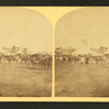 View of a fairgrounds(?), showing people and large tents.