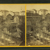View of town with dam in foreground, churches, homes, other buildings.