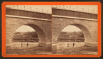 View of two people standing under completed arch.