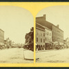 View of unidentified street with businesses and horse-drawn carts.