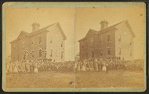 View of unidentified students and teachers in front of wood frame school.