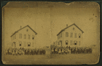 View of unidentified students and teachers in front of wood frame school.